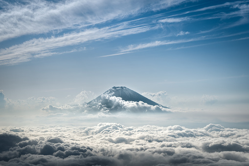 Distant aerial view of Fuji mountain in Japan peaking above the clouds.