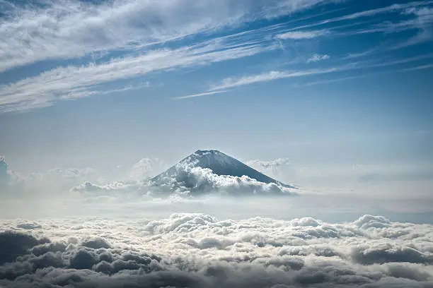 Distant aerial view of Fuji mountain in Japan peaking above the clouds.