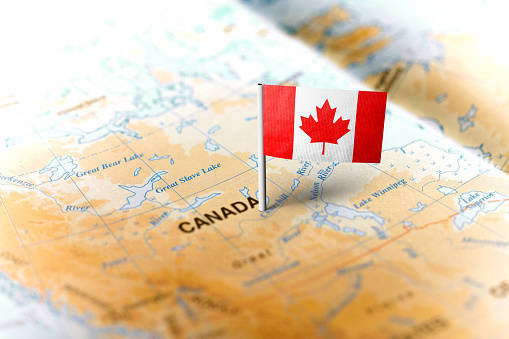 The flag of Canada pinned on the map. Horizontal orientation. Macro photography.