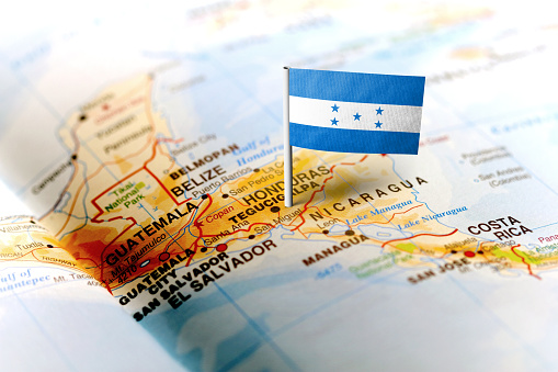 The flag of Honduras pinned on the map. Horizontal orientation. Macro photography.