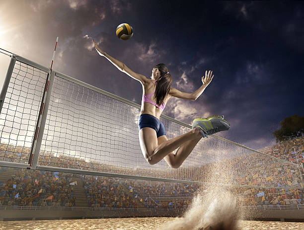 Volleyball: Female player in action Beautiful female volleyball player performs an emotional game moment on the sand volleyball stadium with bleachers full of people. She is wearing an unbranded sports cloth. womens field event stock pictures, royalty-free photos & images