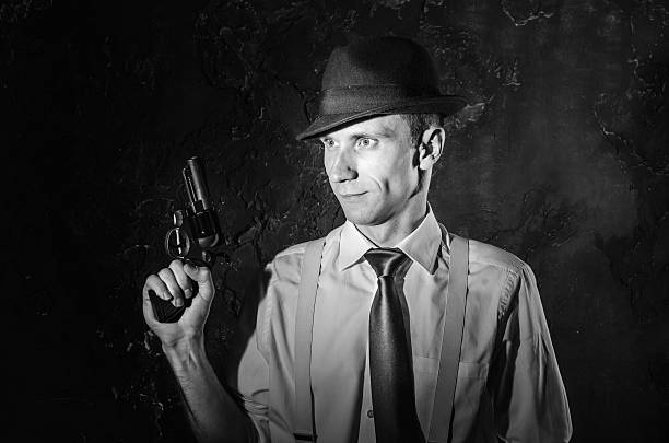 istock Handsome detective in hat holding a gun in the dark 583796400