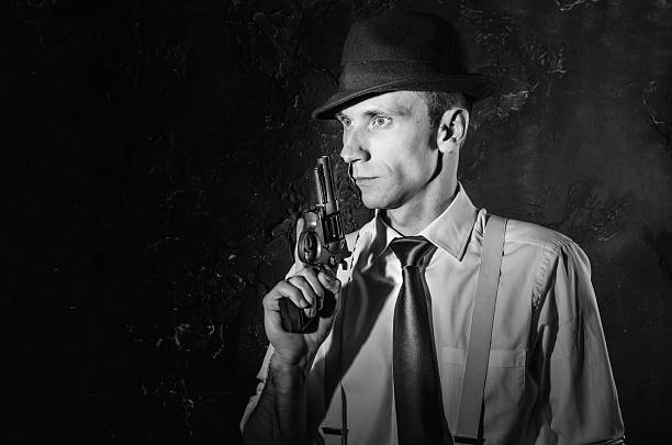 istock Handsome detective in hat holding a gun in the dark 583796434