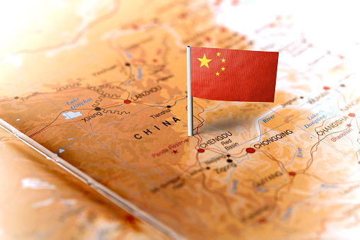 The flag of China pinned on the map. Horizontal orientation. Macro photography.