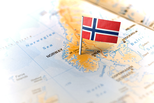 The flag of Norway pinned on the map. Horizontal orientation. Macro photography.