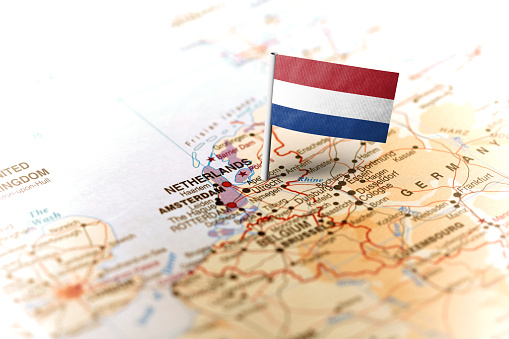 The flag of Netherlands pinned on the map. Horizontal orientation. Macro photography.