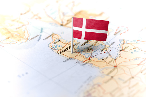 The flag of Denmark pinned on the map. Horizontal orientation. Macro photography.