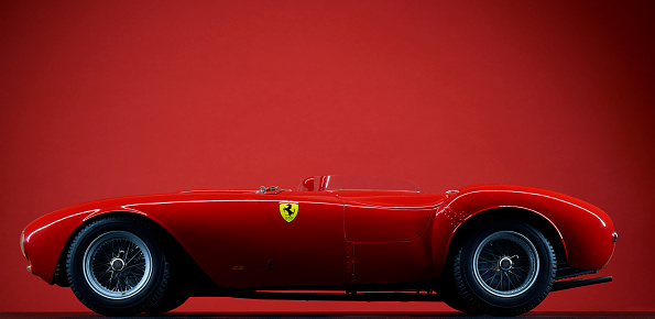 London, England - July 27, 2016: The side view of a scale model of the 1954 Ferrari 375 Plus against a red background.
