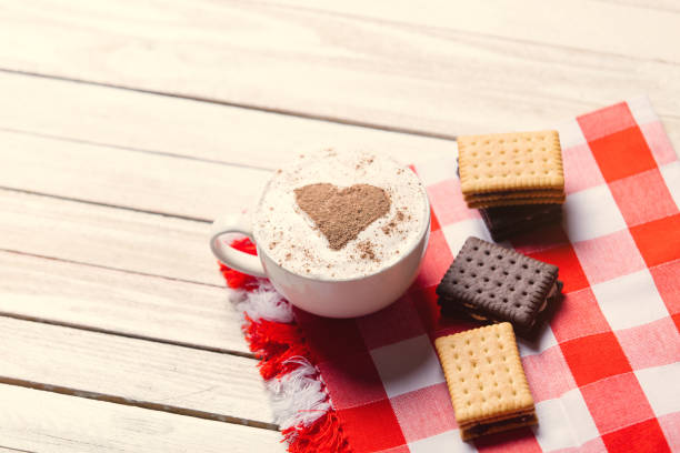 A cup of hot chocolate with a heart shaped marshmallow - red satin background