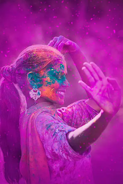 Young woman covered in colored dye celebrating Holi festival in Jaipur, India.