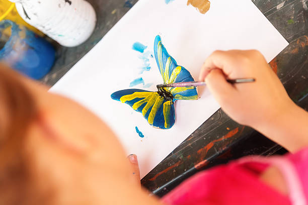 istock Girl paints a butterfly 583812408