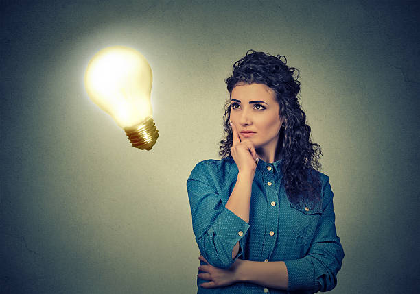 istock Woman thinking looking up at bright light bulb 583814094