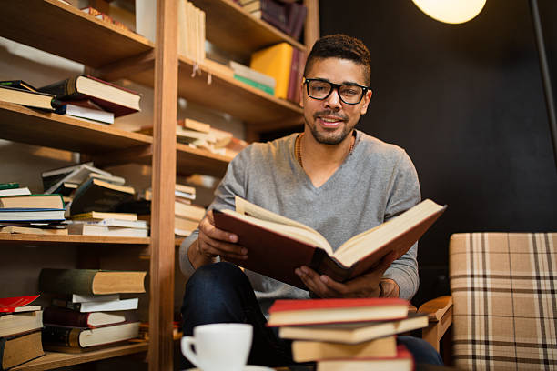 istock Smiling African American student reading a book in library. 583815164