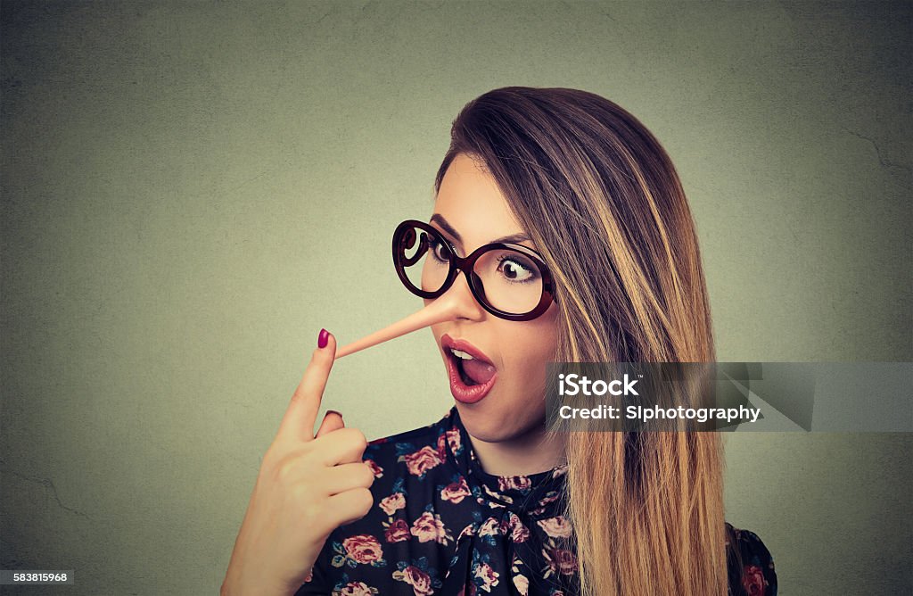 Woman with long nose. Liar concept. Woman with long nose isolated on grey wall background. Liar concept. Human face expressions, emotions, feelings. Dishonesty Stock Photo