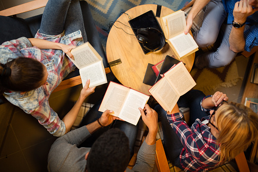 Grupo diverso de amigos discutiendo un libro en la biblioteca. photo