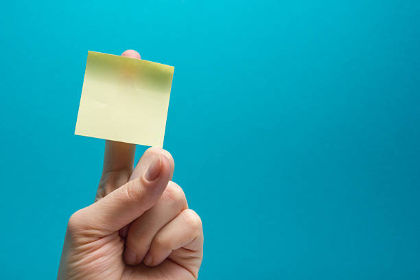 sticky note, finger up of thumb, yellow reminder on blue - thumbtack bulletin board blue office supply imagens e fotografias de stock