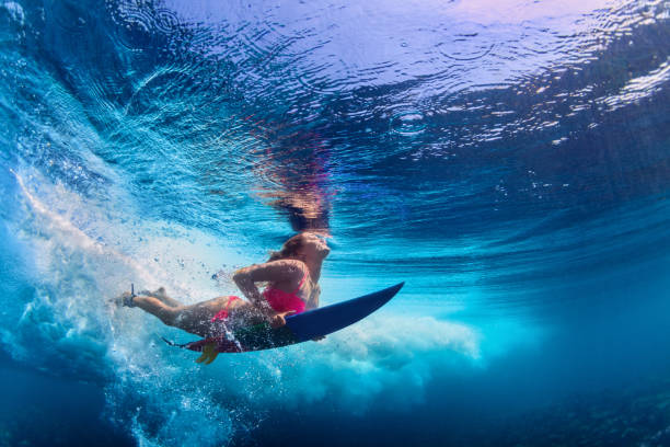 linda surfista menina mergulhando debaixo d'água com prancha de surf - esporte aquático - fotografias e filmes do acervo