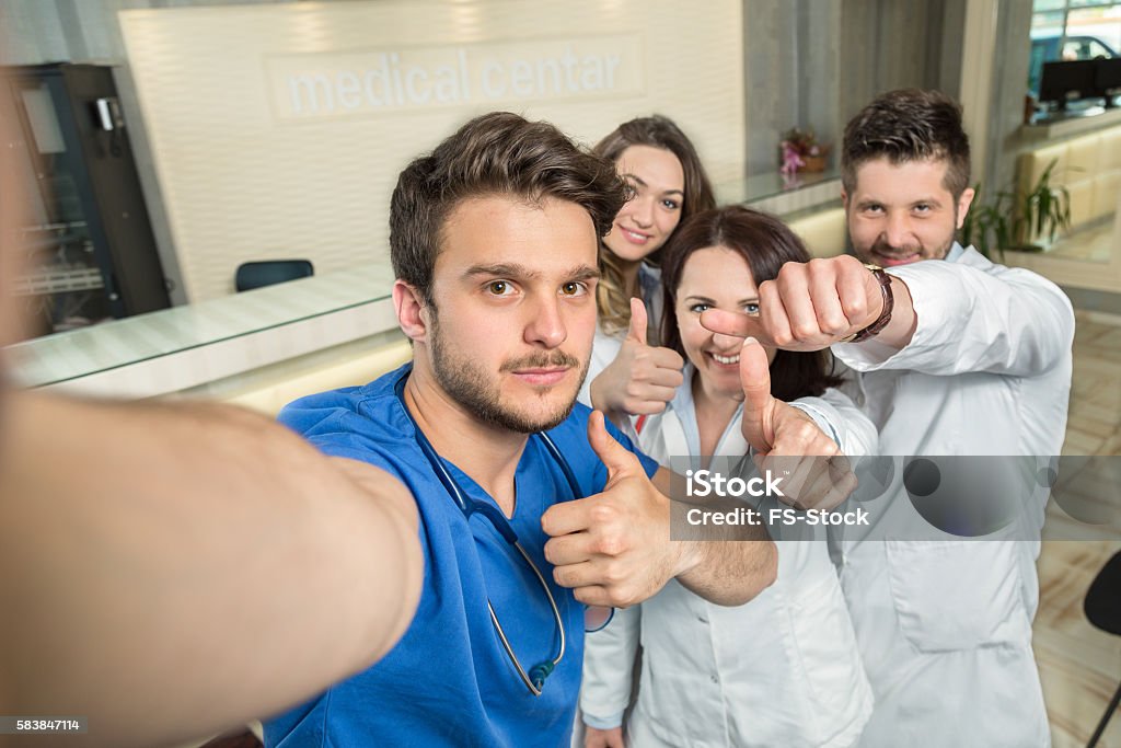 Smiling Team Of Doctors And Nurses At Hospital Taking Selfie Smiling Team Of Doctors And Nurses At Hospital Taking Selfie. Hospital Stock Photo