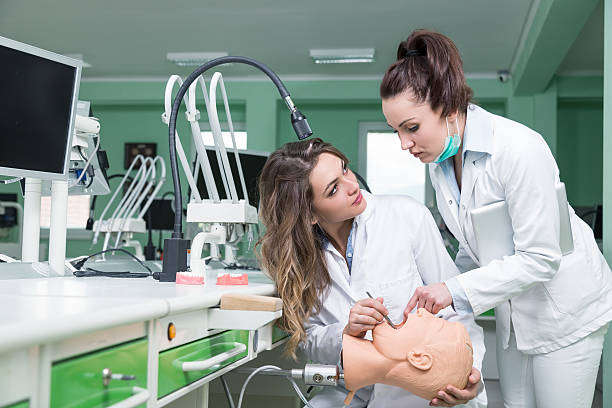 Smiling dentistry teacher standing in front of her student.