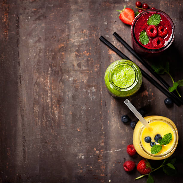 glasses of various smoothies with straws and fruits