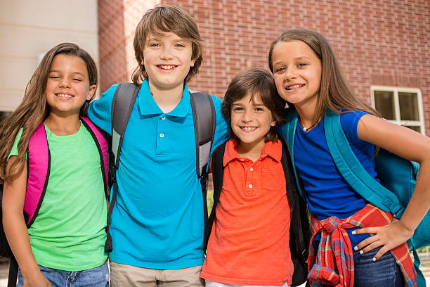 istock Elementary-age children, friends on school campus going back to school. 583849022