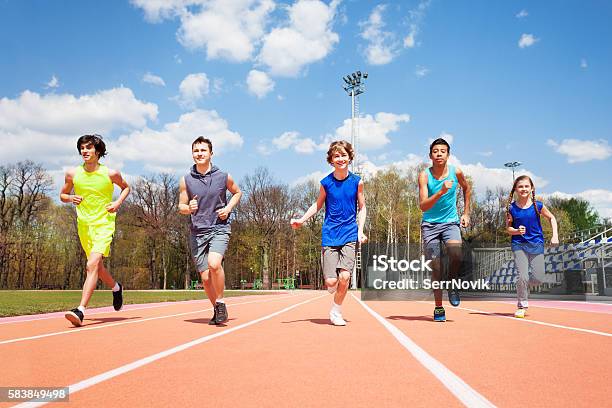 Cinco Velocistas Adolescentes Corriendo Juntos En Una Pista Foto de stock y más banco de imágenes de Niño