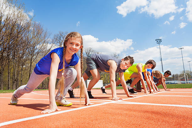 Group of teenage runners lined up ready to race Side view of five teenage sprinters in sportswear lined up ready to race at the stadium track and field stock pictures, royalty-free photos & images