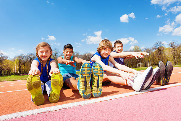 istock Happy kids doing stretching exercises on a stadium 583851114