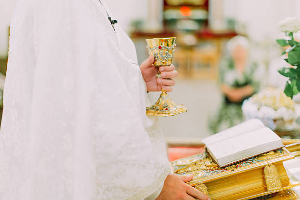 istock Priest hands during open air mass, Bible and cup of 583852210