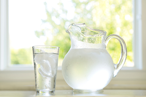 A water pitcher and glass on a kitchen countertop