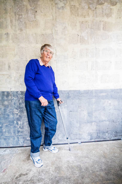 istock Senior woman standing at a wall with crutch 583853236