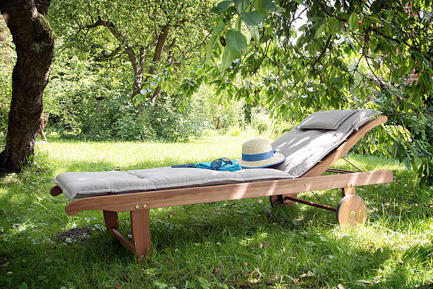 garden daybed of wood on a sunny meadow between trees - sunbed imagens e fotografias de stock