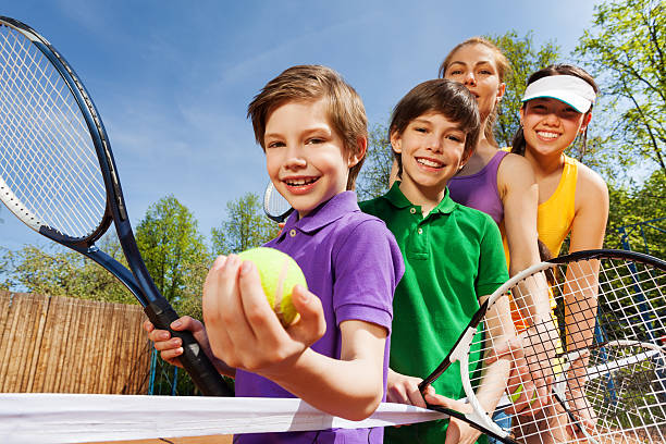 familia jugando al tenis sosteniendo raquetas y pelota - tennis women action lifestyles fotografías e imágenes de stock