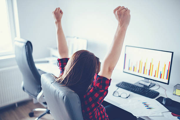 Portrait of happy young successful businesswoman celebrate something with arms up. Happy woman sit at office and look at Computer/ laptop. Positive emotion. Big deal, promotion, lottery win or discount concept