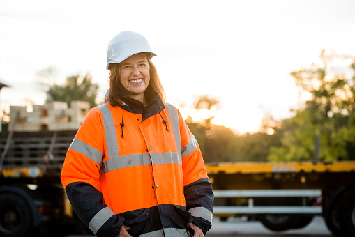 Portrait of mature woman engineer wearing protective orange jacket in work