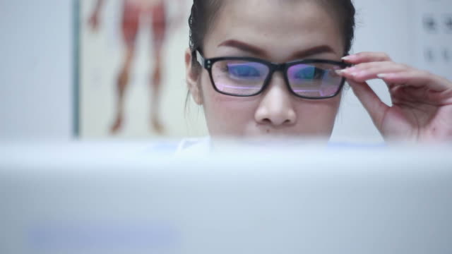 Close up shot of doctor wearing glasses using computer