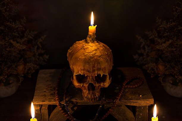 crâne avec lumière de bougie dans la nuit sombre - crâne en cire porte bougie photos et images de collection