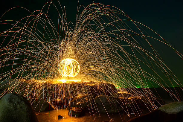 istock Hot Golden Sparks Flying from Man Spinning Burning Steel Wool 583959600