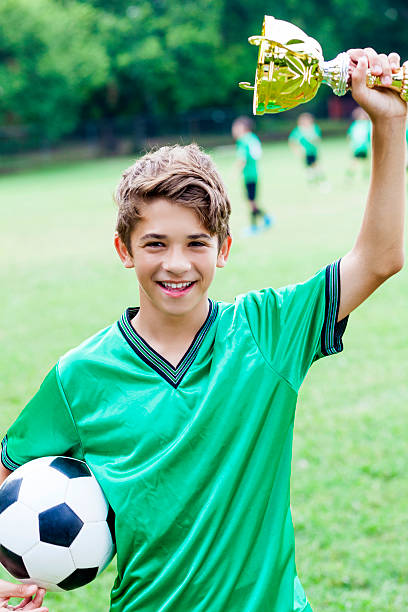 istock Victorious soccer player holding up a big gold trophy 583960702