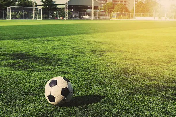 Photo of Old soccer ball on green grass, vintage tone