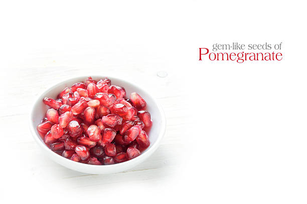 istock seeds of pomegranate in a bowl, white wood, sample text 583968526