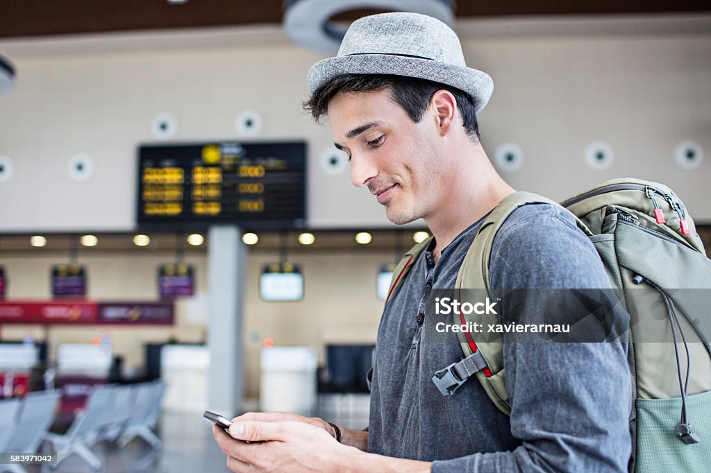 Young man with backpack and cell phone in airport Young man with backpack and cell phone waiting in airport. Airport Stock Photo