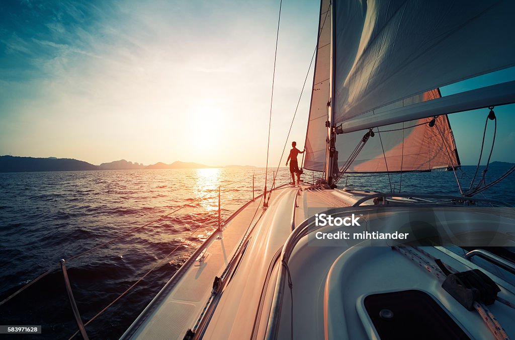 Man on the yacht Young man standing on the yacht in the sea at sunset Sailboat Stock Photo