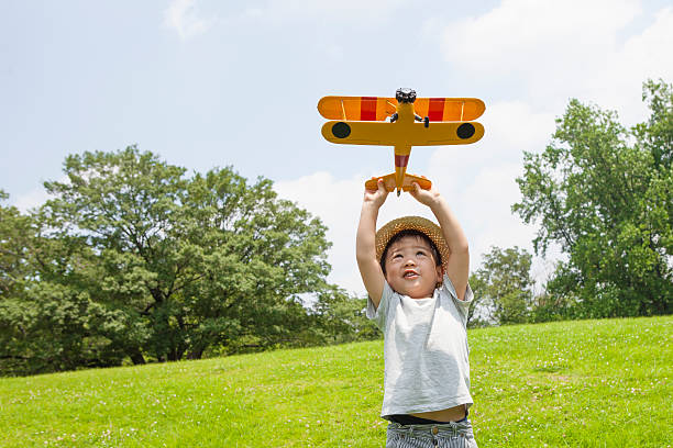 junge spielt mit einem flugzeug von spielzeug im park - child discovery outdoors playing stock-fotos und bilder