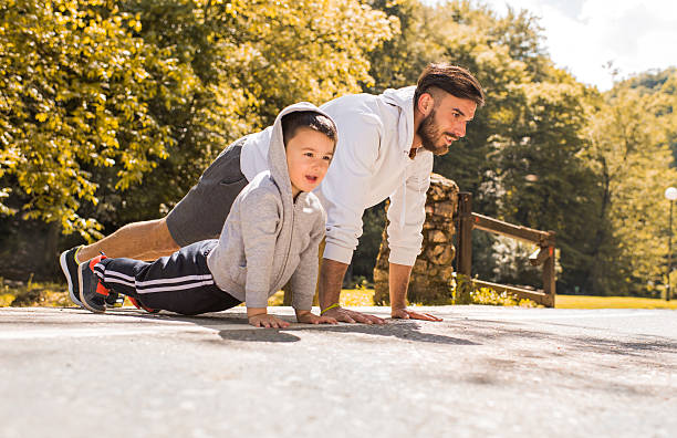 istock Father and son exercising push-ups in the park. 583976570