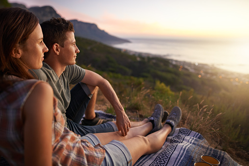 Shot of a young couple watching the sunset together outdoors