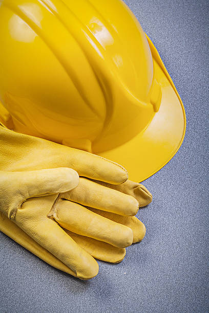 istock Hard hat pair of leather protective gloves on grey background 583983548
