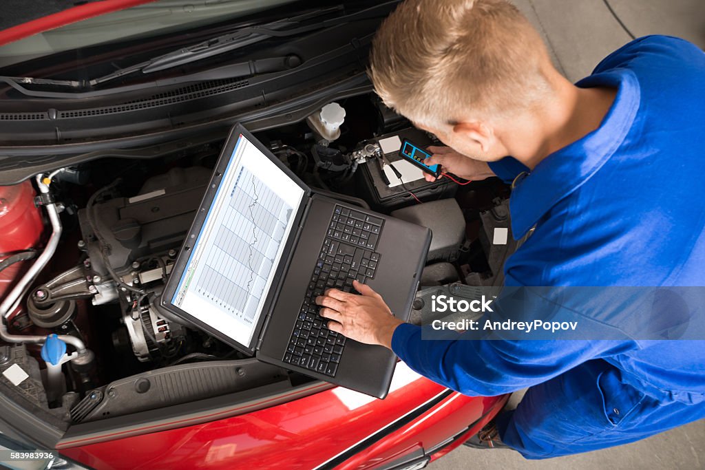 Mechanic Using Laptop To Repair Car High Angle View Of Mechanic Using Laptop To Repair Car In Garage Auto Mechanic Stock Photo