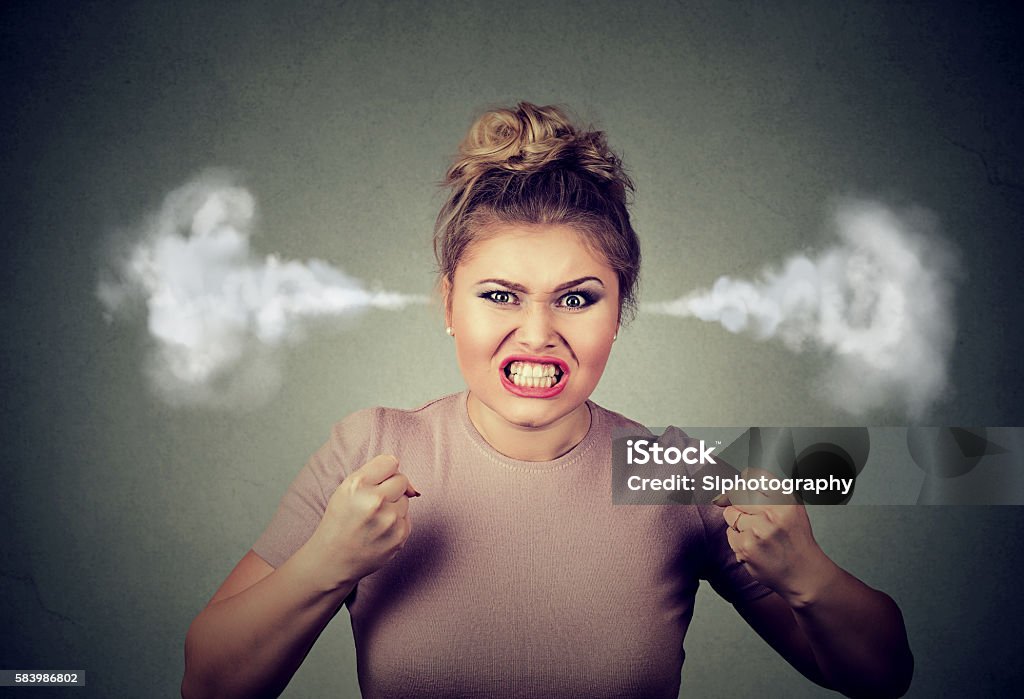 angry woman blowing steam coming out of ears Closeup portrait angry young woman blowing steam coming out of ears, about to have nervous atomic breakdown screaming isolated black background. Negative human emotion face expression feeling attitude Anger Stock Photo