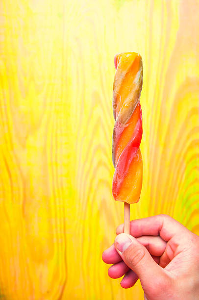 Colorful ice lolly in hand on green wooden background
